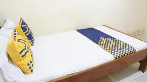 a white bed with blue and yellow pillows on it at Hotel O Homestay Srikandi Pulau Merah BeachNearPantai Pancer in Pasanggaran +17 photos