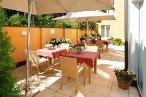 Un patio con mesas y sillas y una sombrilla. en Best Western Hotel Lippstadt, en Lippstadt