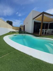 a swimming pool in the grass next to a house at Casa Vacacional Villa Liberty in Corralejo