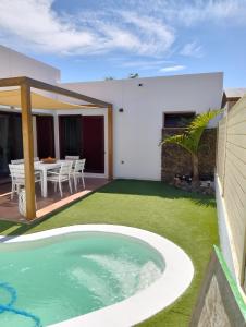 a backyard with a swimming pool and a house at Casa Vacacional Villa Liberty in Corralejo