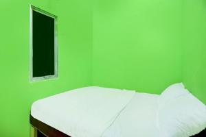 une petite chambre verte avec un lit avec une fenêtre dans l'établissement Hotel O Joyoakis 2 Homestay SyariahNearMall Nagoya Hill, à Nagoya