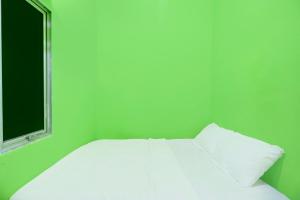 - un lit blanc dans une chambre verte dotée d'une fenêtre dans l'établissement Hotel O Joyoakis 2 Homestay SyariahNearMall Nagoya Hill, à Nagoya