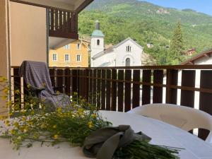 a table with flowers on a balcony with a church at My 3 stars BEE HAPPY studio in Brides-les-Bains