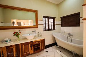 a bathroom with a tub, sink, mirror and bathtub at Kleinkaap Boutique Hotel in Centurion