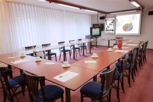 una sala de conferencias con mesas, sillas y una pantalla en Hotel Zur Linde, en Schermbeck