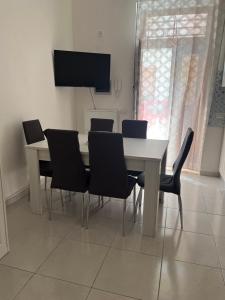 stół jadalny z czarnymi krzesłami i telewizor w obiekcie B&B Regina Rooms w mieście Avola
