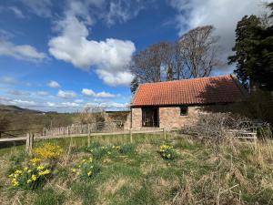 una vecchia casa con un tetto rosso in un campo di Stable Cottage by Roslin Glen a Roslin