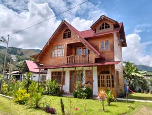 a wooden house with a balcony on a lawn at La Cabaña de Mari in Oxapampa