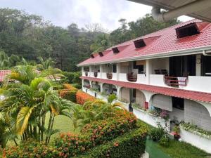 a building with a red roof and a garden with flowers at Samara Beach Las Palmeras Condo with Ocean view in Sámara