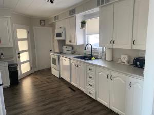 a kitchen with white cabinets and a wooden floor at Bernice Mae's Ocean View in Lewisporte