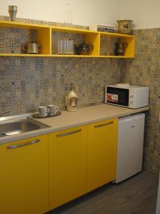 a yellow kitchen with a sink and a microwave at The Kiss Apartment in Timişoara +6 photos