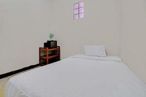a white bed in a white room with a window at OYO Life 92709 Kost Teras Cikapundung Syariah in Bandung