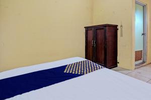 a bedroom with a bed and a wooden cabinet at Hotel O Lili Kost SyariahNearKetapang Royal City in Banyuwangi
