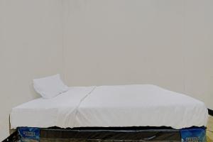 a bed with white sheets and a pillow on it at OYO Life 92709 Kost Teras Cikapundung Syariah in Bandung