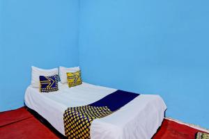 a bed with yellow and blue pillows on it at Hotel O Lestari Syariah in Sidoarjo