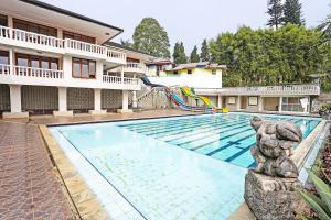 a swimming pool with a slide next to a house at Hotel O Tjokro 3 in Bogor