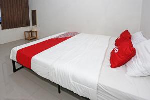 a bed with a red pillow on top of it at Hotel O Tjokro 3 in Bogor