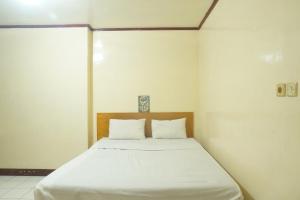 une chambre avec un lit avec des draps blancs dans l'établissement Hotel O Rumah Massagena Syariah Near Gedung Olahraga Enrekang, à Enrekang