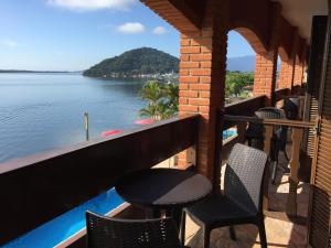 a balcony with chairs and a table and a view of the water at Hotel Marazul in Cananéia