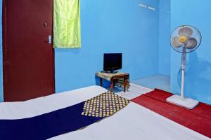 a bedroom with a bed with a fan and a television at Hotel O Lestari Syariah in Sidoarjo
