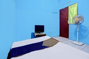 a bedroom with a bed and a door with a fan at Hotel O Lestari Syariah in Sidoarjo