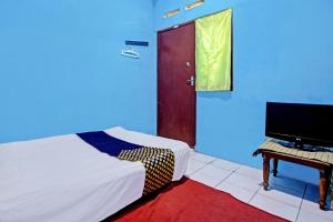 a bedroom with a bed and a tv and a door at Hotel O Lestari Syariah in Sidoarjo +20 photos