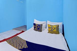 a bed with yellow and blue pillows on it at Hotel O Lestari Syariah in Sidoarjo