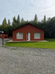 a small red house with a grassy yard at Cabaña Puente B 1 in El Calafate