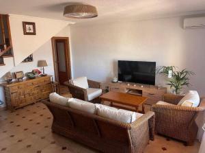 ein Wohnzimmer mit Korbmöbeln und einem Flachbild-TV in der Unterkunft Adosado playa de la Mata con vistas al mar in Torrevieja