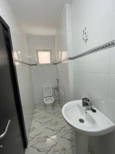 a white bathroom with a sink and a toilet at Sabah Appartment in Essaouira +3 photos
