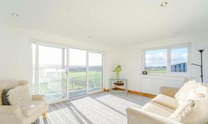 a white living room with a couch and windows at Oswaldtwistle Farmhouse in Oswaldtwistle