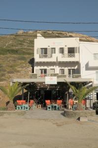 a large white building with orange chairs and tables at Amoudaki Apartments in Agali