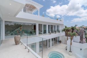 ein großes weißes Haus mit Glaswänden und einem Balkon in der Unterkunft Casa Auma Stunning 4 Bedroom Villa in Canggu in Tumbak Bayuh