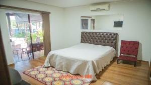 a bedroom with a bed and a red chair at Casa com Piscina e Lazer Completo em Barra Bonita in Igarassú