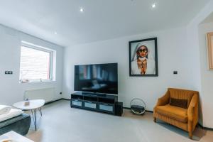 a living room with a flat screen tv and a chair at Grand appartement rez de jardin in Guebwiller