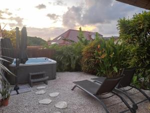 a backyard with a hot tub and two chairs and a grill at Le Colibri in Sainte-Anne