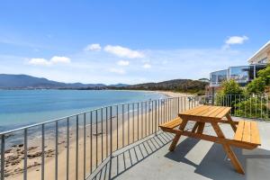 HowrahAbsolute Waterfront Only 15 minutes From Hobart的俯瞰海滩的阳台上的野餐桌