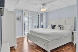 a white bed in a room with a ceiling fan at Shipwatch 115C by Wild Dunes, Oceanfront Condo in Isle of Palms