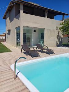 une piscine avec deux chaises et une maison dans l'établissement Casa de Praia com piscina - Porto de Sauipe, à Porto do Sauipe