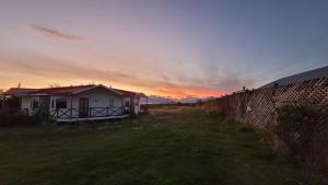 a house in a field with a sunset in the background at Cabañas Patagonia Encantada in Puerto Natales +194 photos