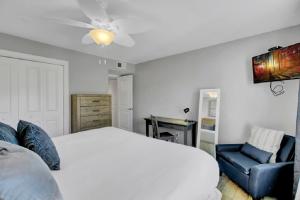 a bedroom with a white bed and a blue chair at Seagrove 1A by Wild Dunes, Oceanfront Condo in Isle of Palms