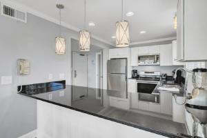 a kitchen with white cabinets and stainless steel appliances at Seagrove 1A by Wild Dunes, Oceanfront Condo in Isle of Palms