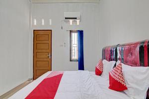 a bedroom with a bed with red and white pillows at Hotel O Lestari Baru Syariah Near SMA Negeri 1 Salo in Bangkinang