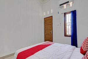 a bedroom with a bed and a window at Hotel O Lestari Baru Syariah Near SMA Negeri 1 Salo in Bangkinang
