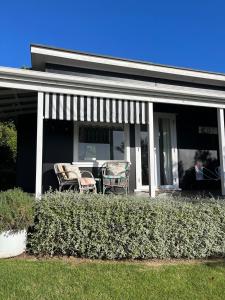 two chairs on the front porch of a house at Rosies cottage hideaway in Stanmore Bay with lovely seaview in Whangaparaoa