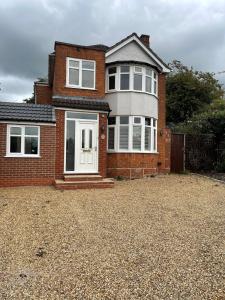 a brick house with a white door on a gravel driveway at Luxury Detached holiday home Near BHX, JLR, NEC in Birmingham