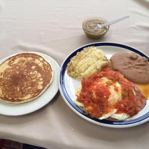 a table with a plate of breakfast food and pancakes at Hotel Posada del Yaqui in Ciudad Obregón