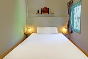 a bedroom with a large white bed with two lamps at OYO 92825 Kamar Lombok in Kuripan
