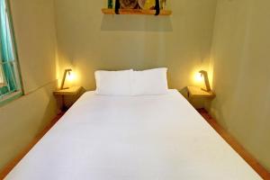 a white bed in a small room with two lamps at OYO 92825 Kamar Lombok in Kuripan