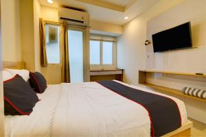 a bedroom with a bed and a tv on the wall at Collection O 92870 Apartement Grand Sentraland Karawang By Ipul in Karawang